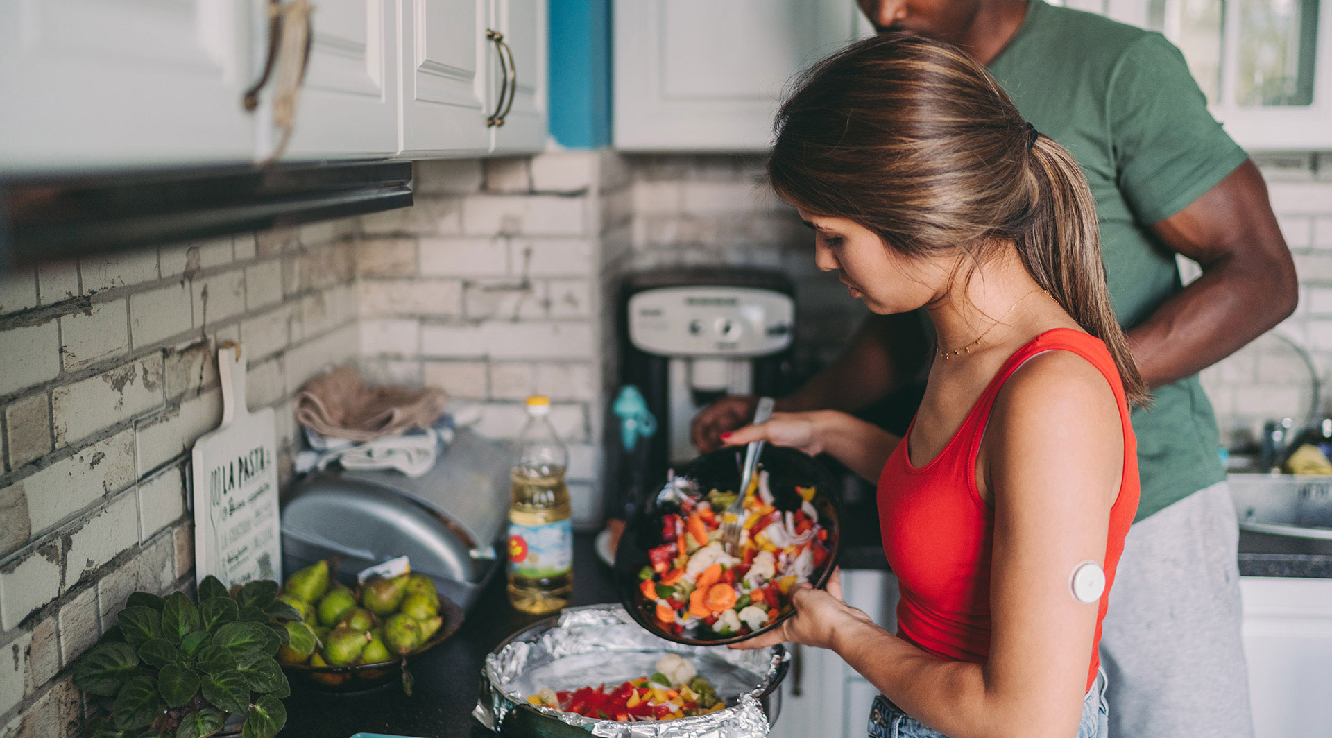 Couple cooking a meal together, female is wearing a diabetes monitor